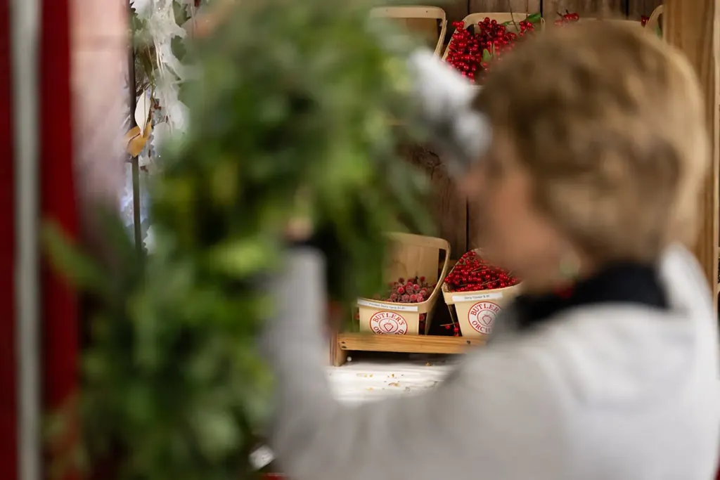 A farm worker's hands gathering fresh evergreen boughs at the farm market.